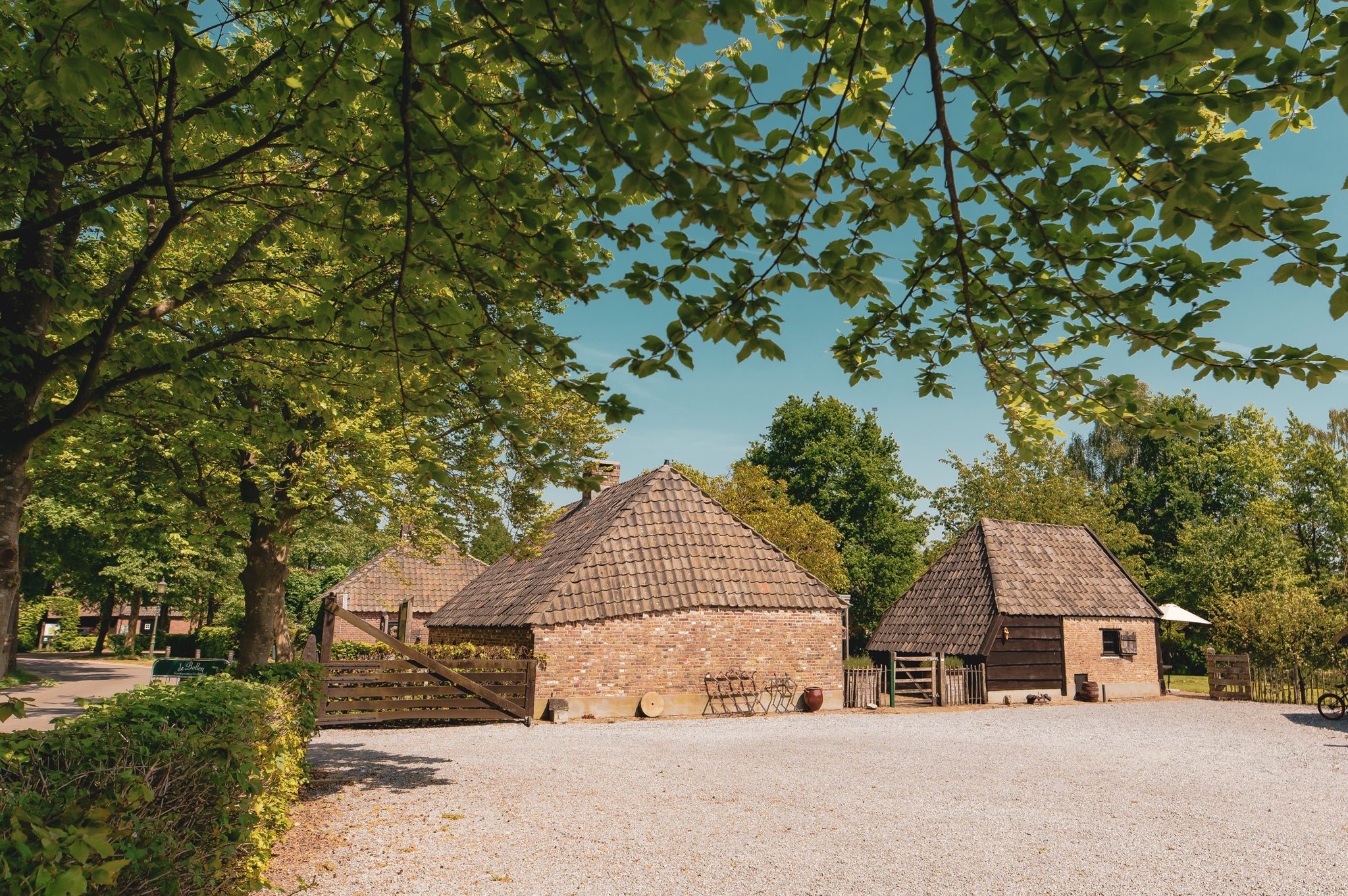 The grounds of Buitengoed de Bollen with historic Brabant outbuildings under tall trees